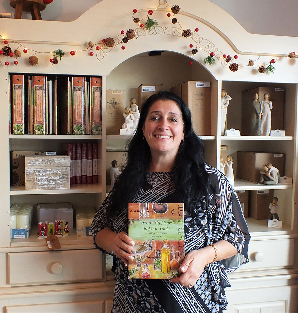 Store owner Tina Fino holds her cookbook of family recipes – From My Heart to Your Table.